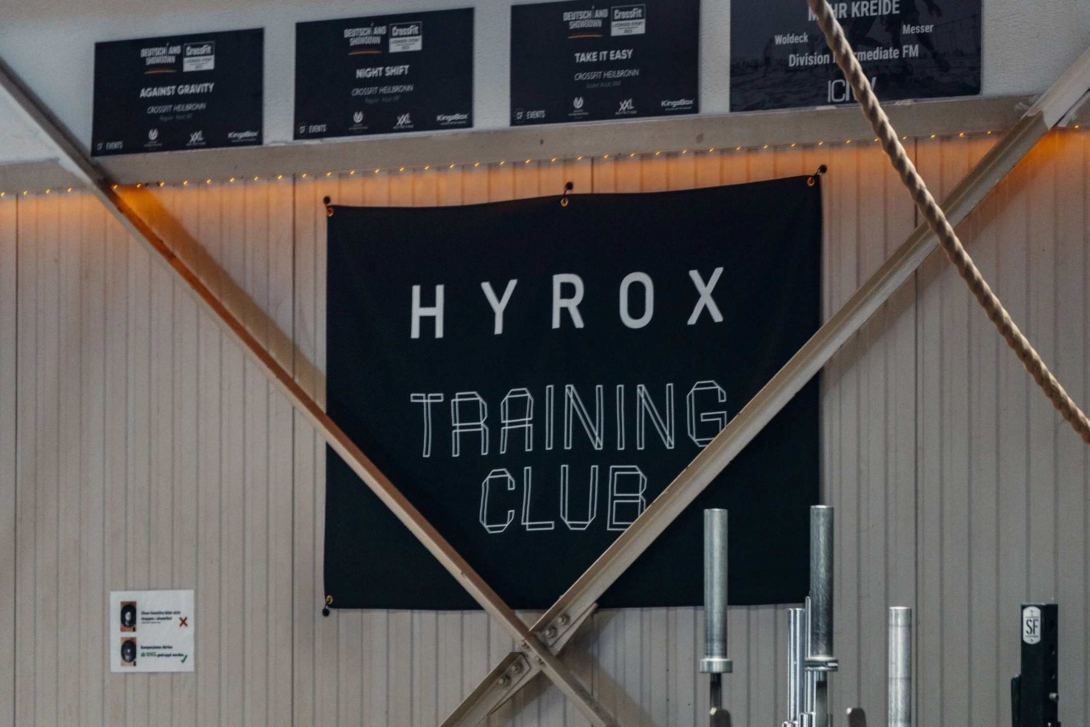 Ein schwarzes Banner mit der Aufschrift „HYROX Training Club“ hängt in der Trainingshalle von CrossFit Heilbronn.