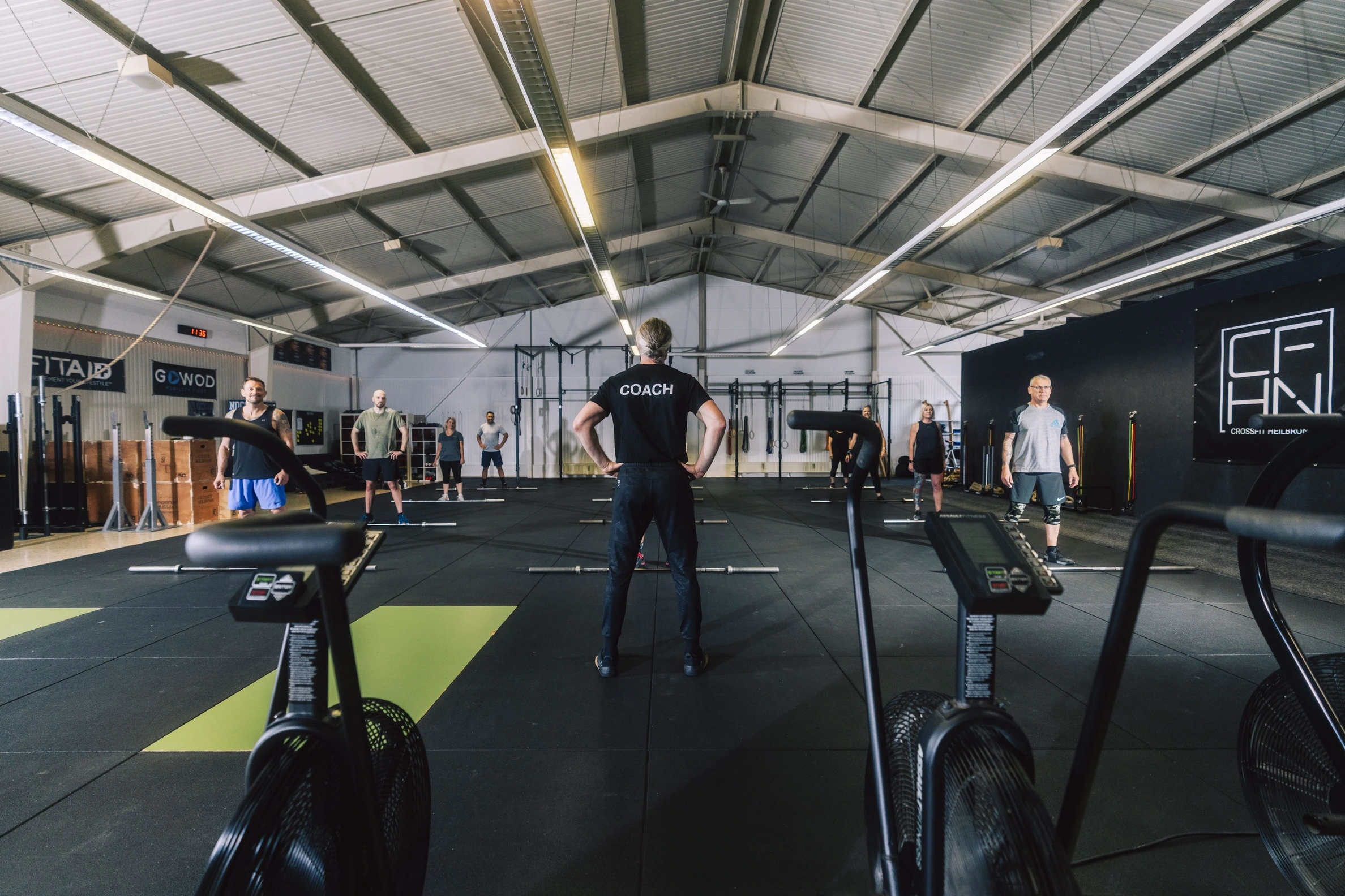 Ein Coach steht mit dem Rücken zur Kamera vor einer Gruppe Sportler in der CrossFit-Box Heilbronn.