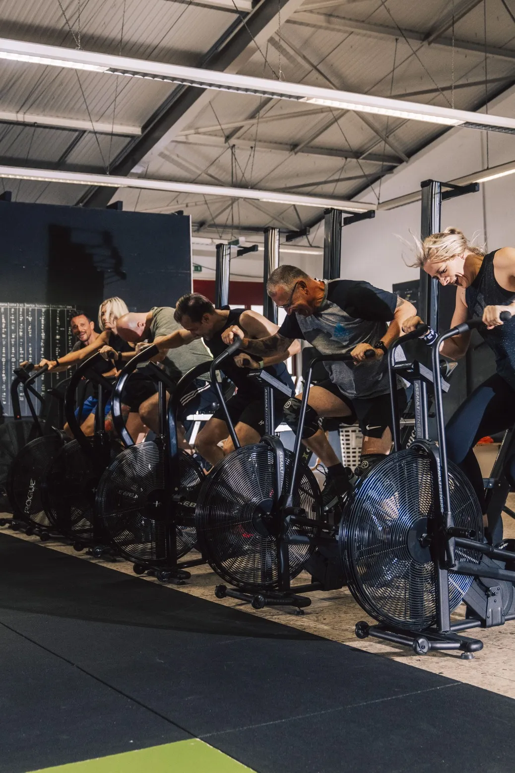 Eine Gruppe trainiert bei CrossFit Heilbronn gleichzeitig auf Airbikes mit voller Intensität.