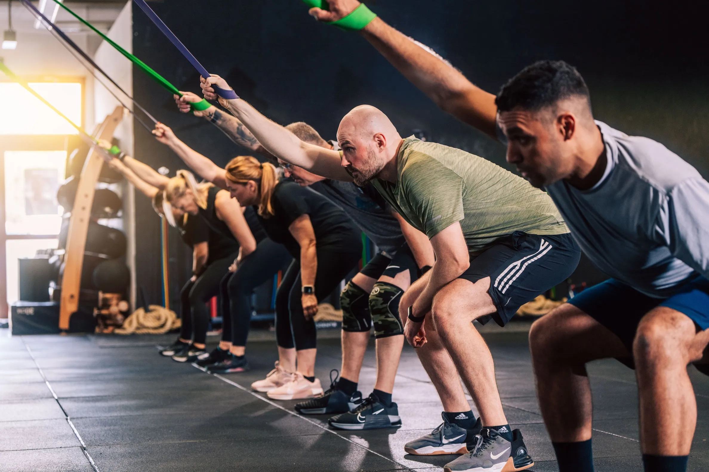 Mehrere Personen führen in der CrossFit-Box Heilbronn Dehnübungen mit Widerstandsbändern aus.