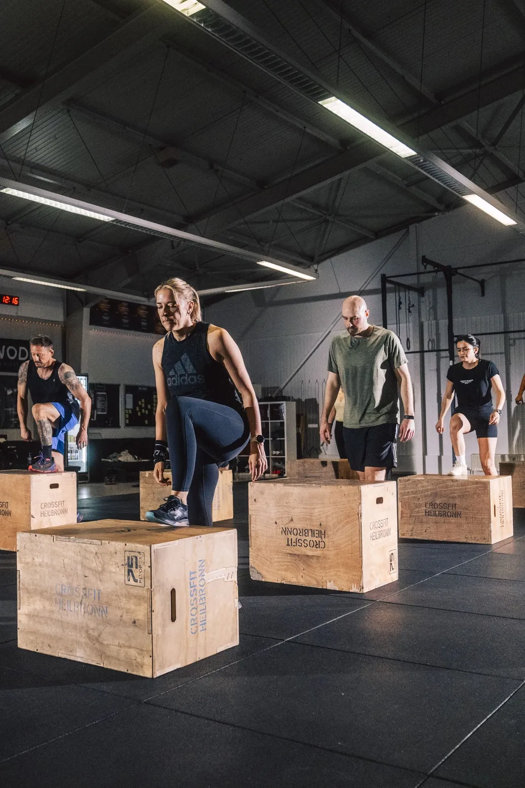 Mehrere Personen machen Step-Ups auf Holzboxen während eines CrossFit-Kurses in Heilbronn.